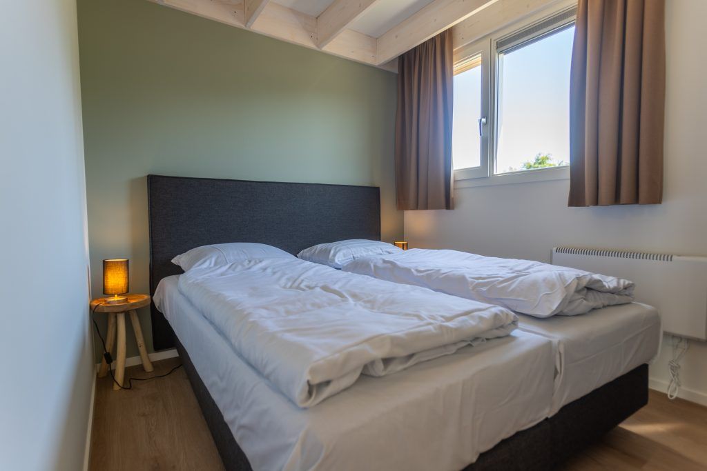 Gezellige slaapkamer in Vrijstaande woning in Cadzand, Zeeuws-Vlaanderen, Zeeland met comfortabel tweepersoonsbed en veel natuurlijk licht.