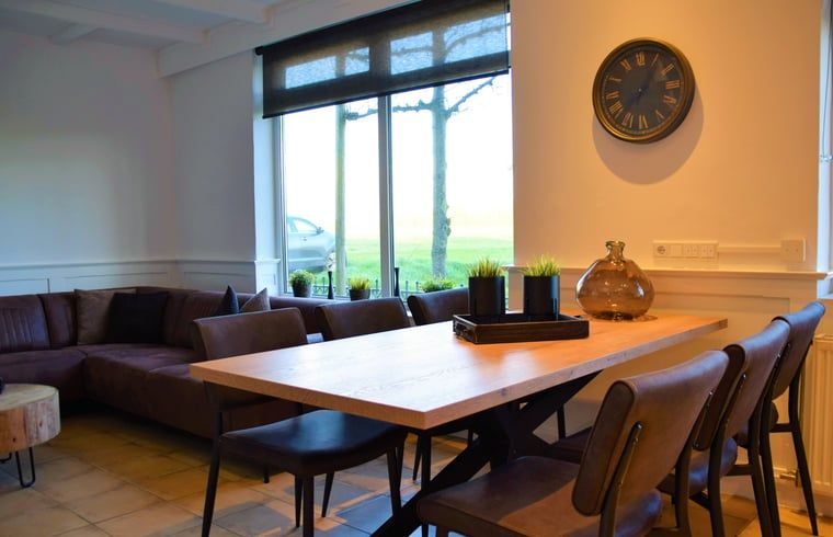 Stilvoller Innenraum des Ferienhauses in Schoondijke, Zeeuws-Vlaanderen, mit grossen Fenstern und einer gemuetlichen Sitzecke.