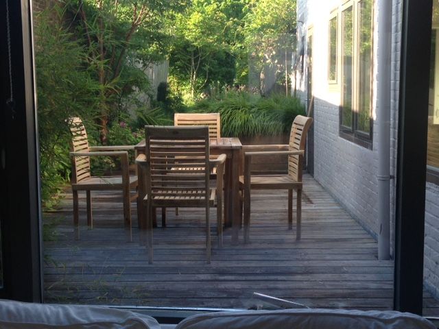 Ruim terras met houten meubels in vakantiehuis Landstraat, Aardenburg, Zeeland, ideaal voor buiten dineren.