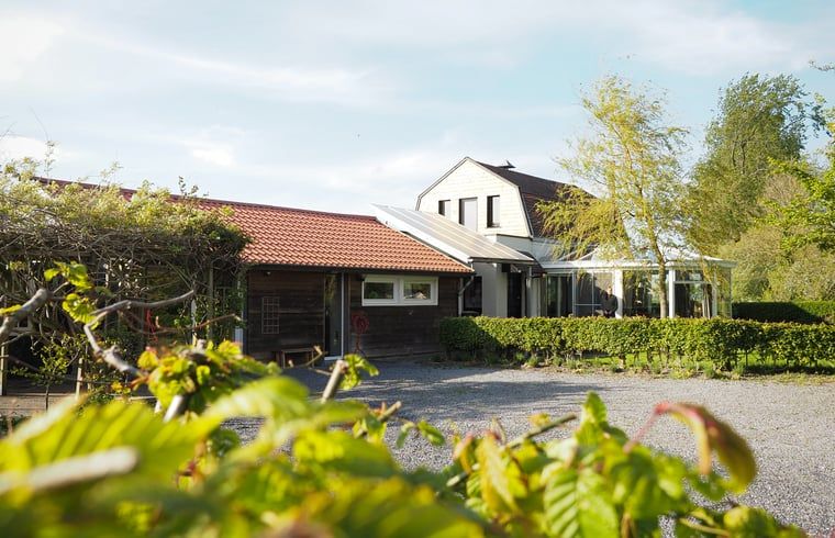 Vakantiehuis in Sluis biedt een rustieke ervaring in Zeeuws-Vlaanderen, Zeeland, omgeven door groene natuur en een zonnig terras.