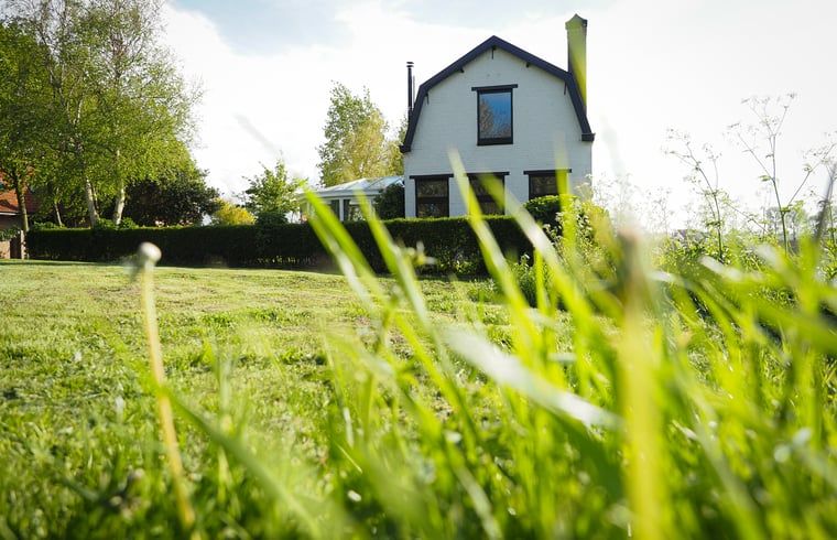 Vakantiehuis in Sluis, Zeeuws-Vlaanderen, omgeven door groene natuur en een uitgestrekt gazon, ideaal voor een ontspannen verblijf.