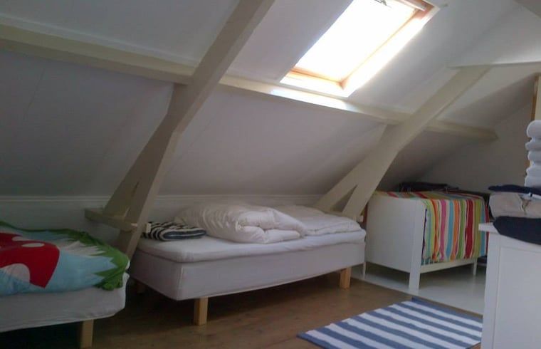 Sfeervolle slaapkamer in Vakantiehuis in Walsoorden, Zeeuws-Vlaanderen, met kleurrijke deken en houten details.