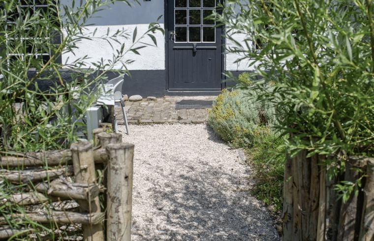 Eingang zum Ferienhaus Walsoorden, Zeeland-Flandern, mit gruener Umgebung und rustikalen Wegen.