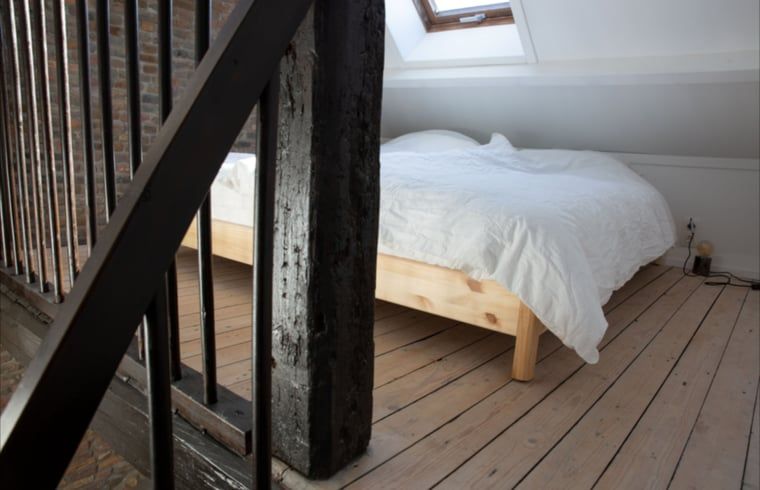 Helles Schlafzimmer im Dachgeschoss des Ferienhauses Walsoorden, Zeeuws-Vlaanderen, mit Holzboden.