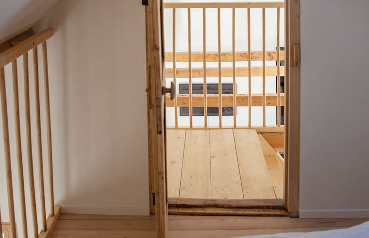 Holztreppe zum Dachgeschoss im Ferienhaus Walsoorden, Zeeuws-Vlaanderen, mit offenem Gelaender.