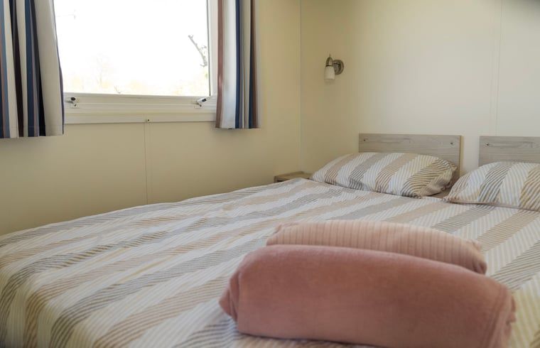 Gezellige slaapkamer in Vakantiehuisje in Hengstdijk, Zeeuws-Vlaanderen, met comfortabel bed en rustgevend uitzicht op de natuur.