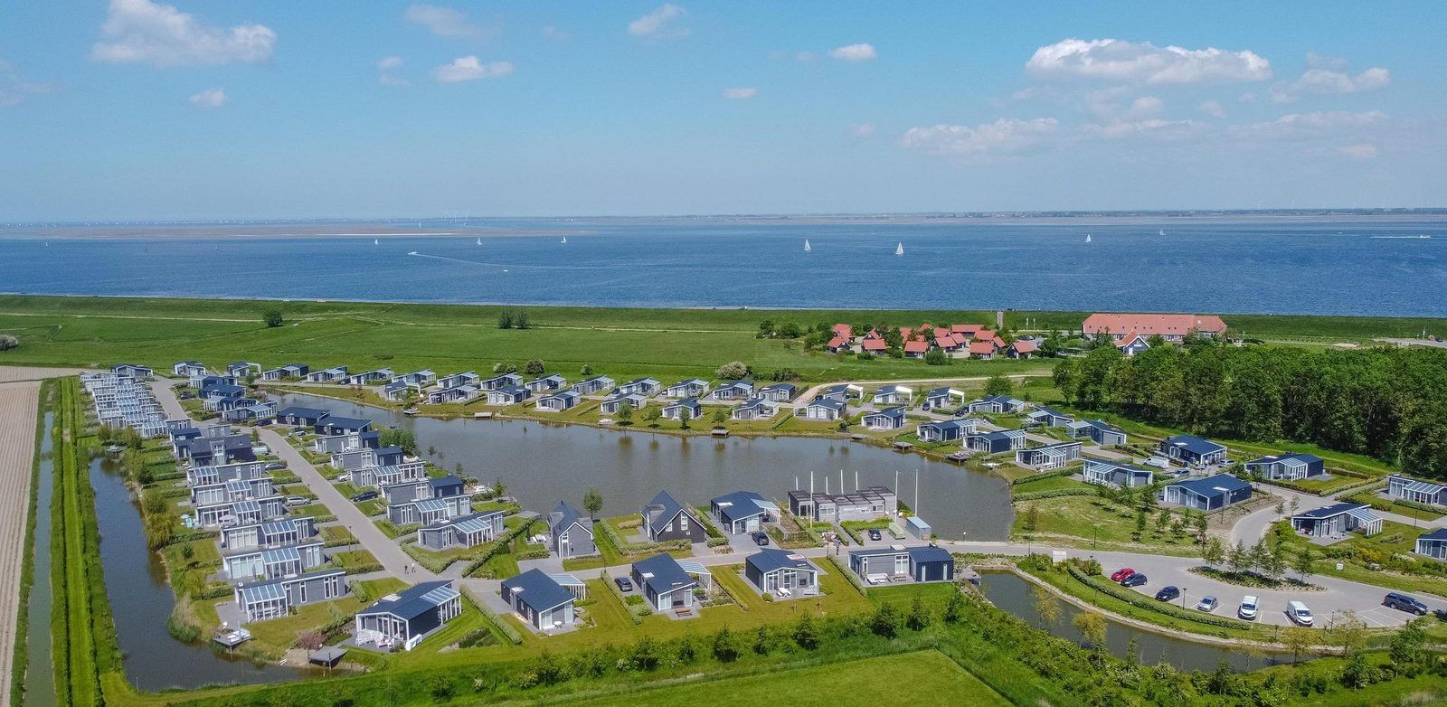 Panoramablick auf Waterresort Oosterschelde in Wemeldinge, Zeeland, mit Ferienhaeusern und Meer.