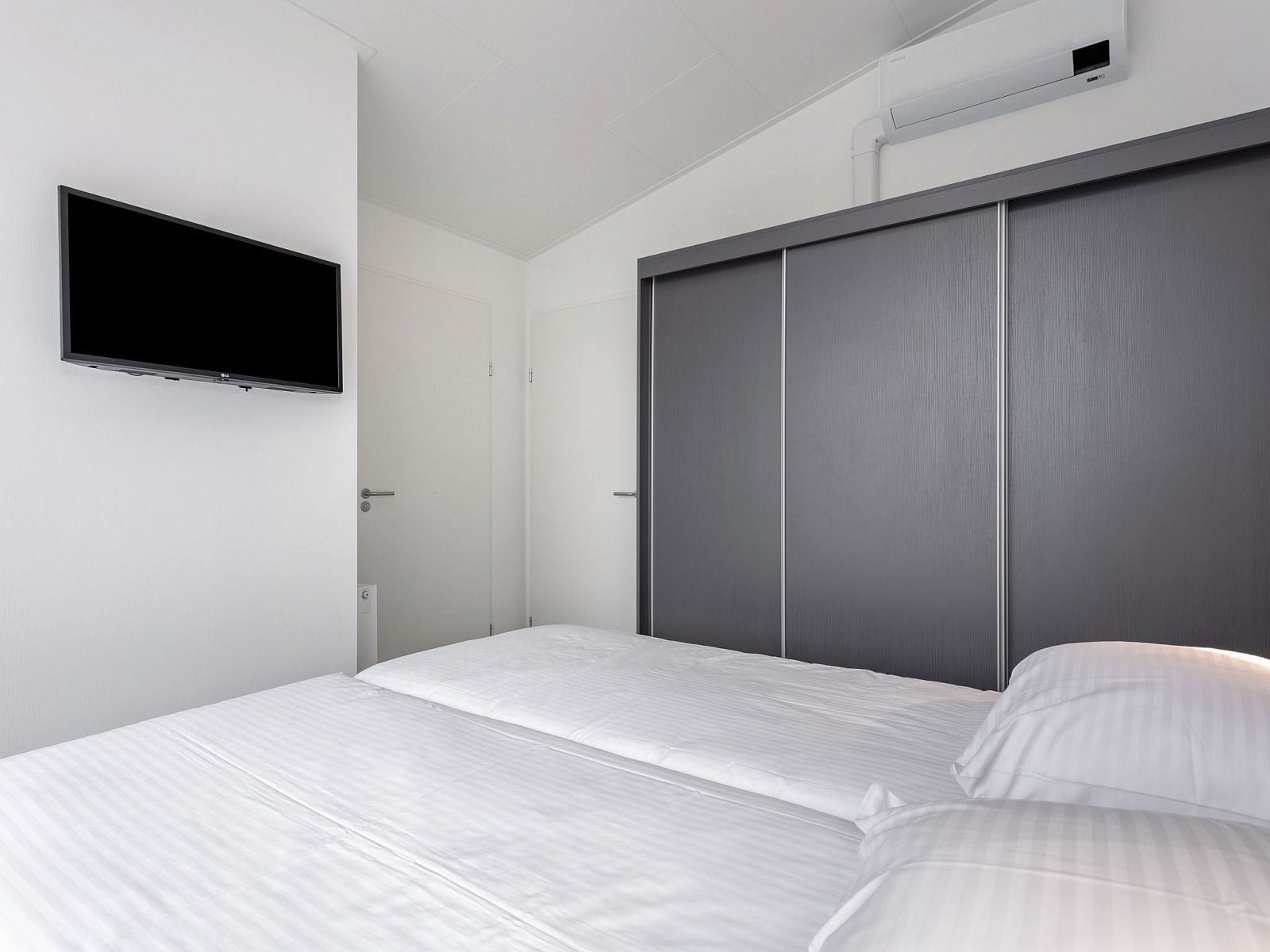 Elegante slaapkamer in Vakantiehuis Ruisweg 12, Wemeldinge, Zuid-Beveland, met tweepersoonsbed en moderne opbergruimte.