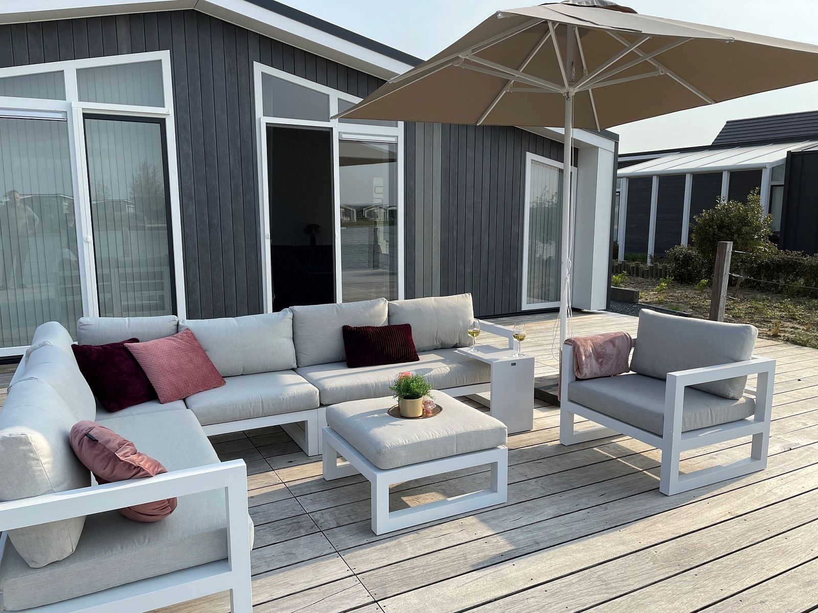 Zonnig terras van Vakantiehuis Ruisweg 12, Wemeldinge, Zuid-Beveland, met comfortabele loungeset en parasol voor ontspanning.