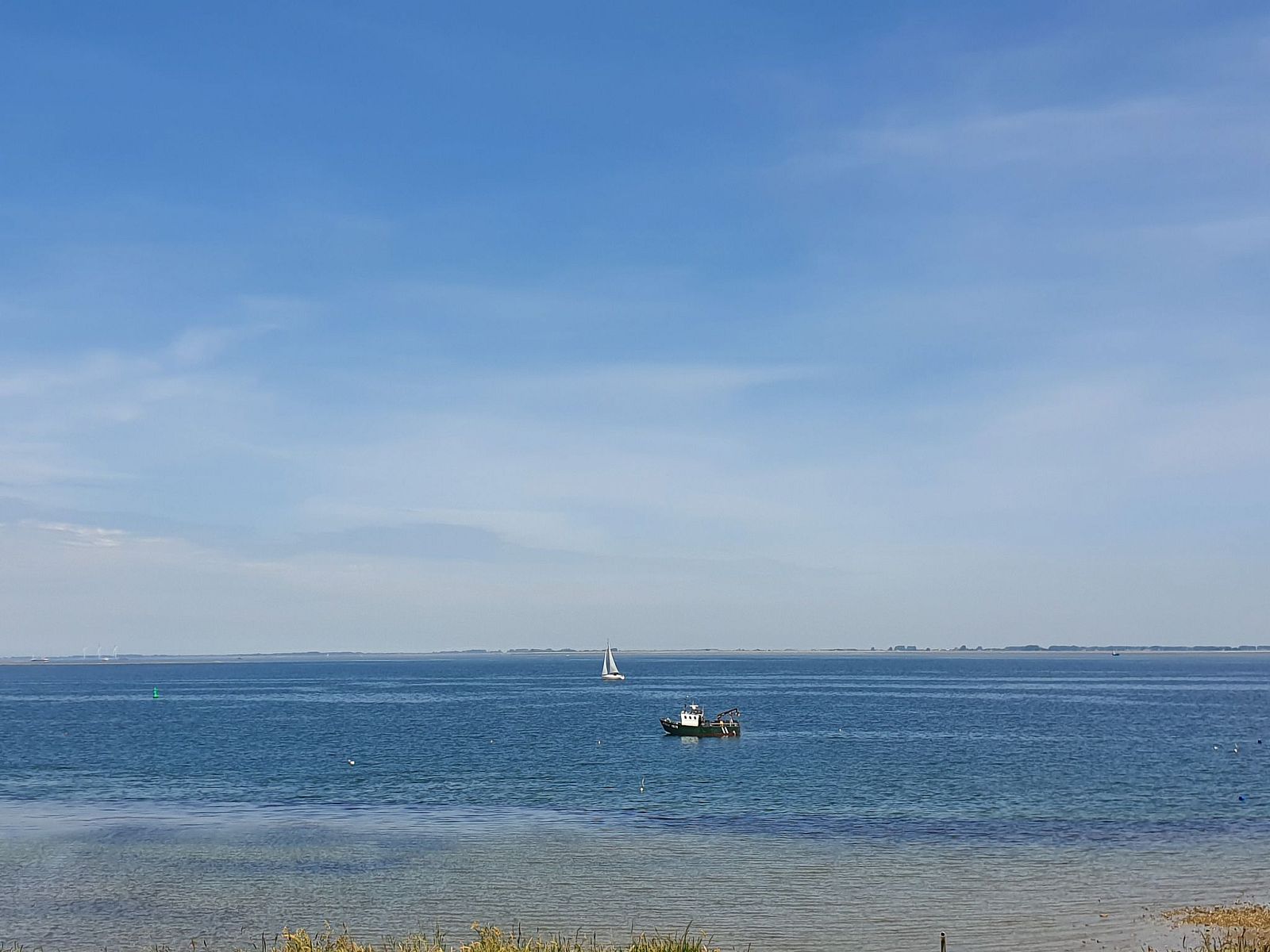 Uitzicht over de Oosterschelde nabij Vakantiehuis Ruisweg 12, Wemeldinge, Zeeland, met zeilboten en blauwe lucht.