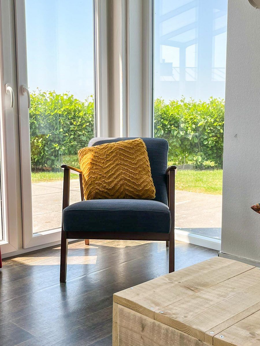 Bequemer Sessel im Wohnzimmer des Ferienhauses Waterresort Oosterschelde Haus Nr. 51 in Wemeldinge, mit Blick auf den Garten.
