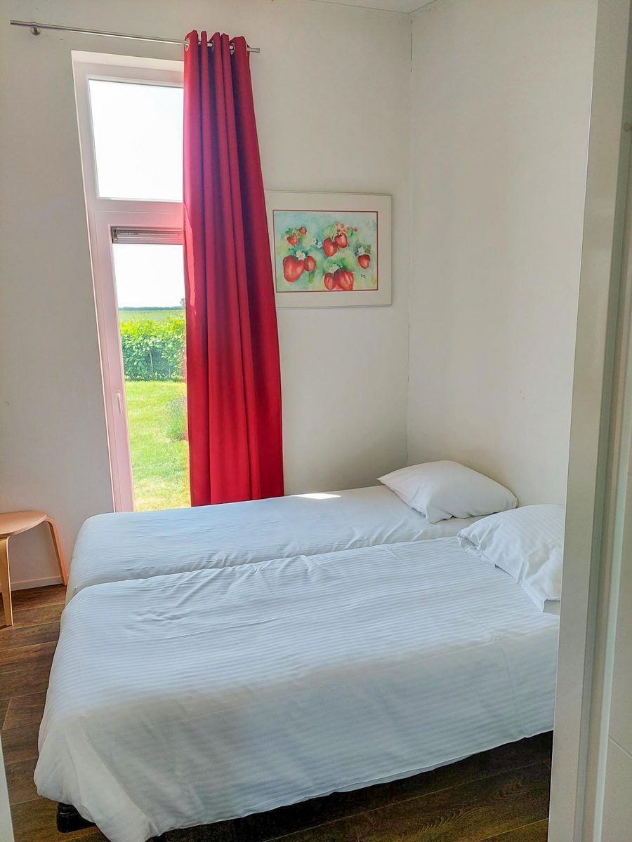 Zweites Schlafzimmer im Ferienhaus Waterresort Oosterschelde Haus Nr. 51, mit hellem Tageslicht und Blick auf gruene Felder.