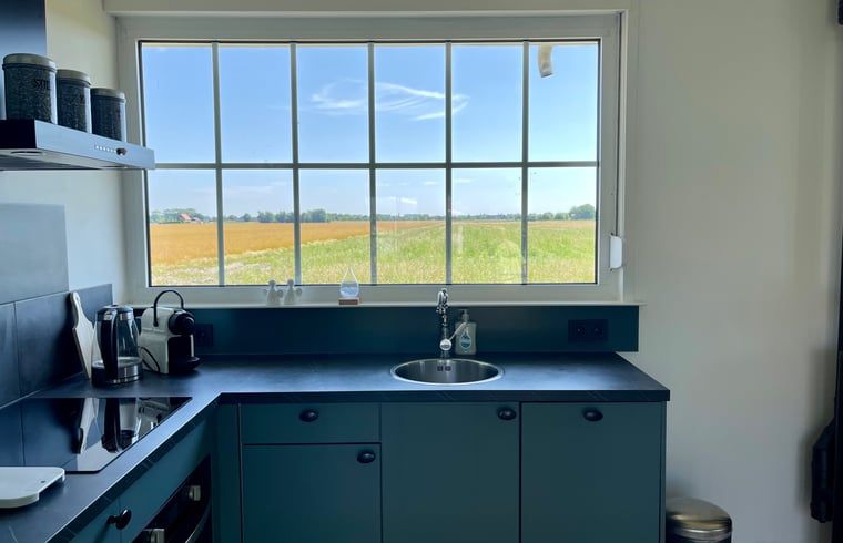 Keukenraam met uitzicht op velden bij Vakantiehuis in Lewedorp, geniet van de natuur in Zuid-Beveland, Zeeland.
