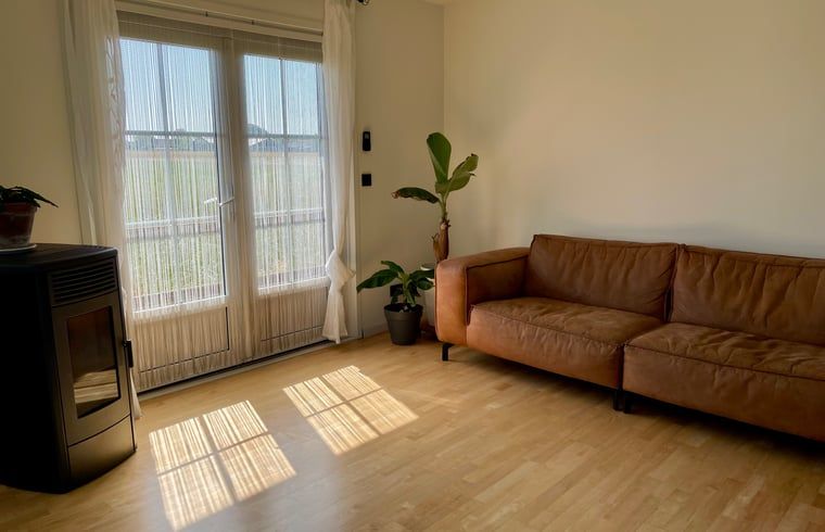 Gezellige woonkamer met leren bank in Vakantiehuis in Lewedorp, ideaal voor ontspanning in Zuid-Beveland, Zeeland.