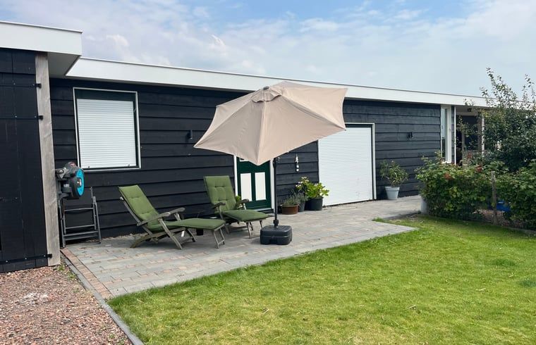 Terras met parasol bij Vakantiehuis in Lewedorp, ideaal voor zonnige dagen in Zuid-Beveland, Zeeland.
