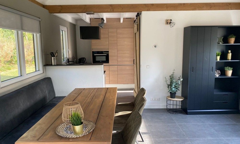 Dining area in vacation home Vrijheid, Ouddorp, Goeree-Overflakkee, South Holland, with wooden table and modern furnishings.