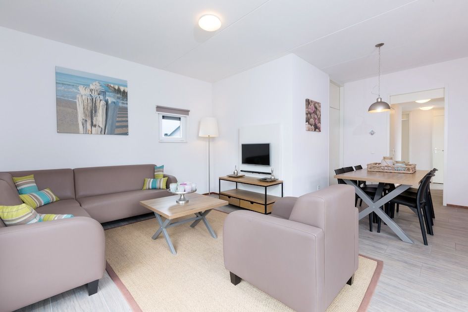 Gemuetliches Wohnzimmer von Bungalow 6C in Ouddorp, Goeree-Overflakkee, Suedholland, mit bequemer Sitzecke und modernem Essbereich.