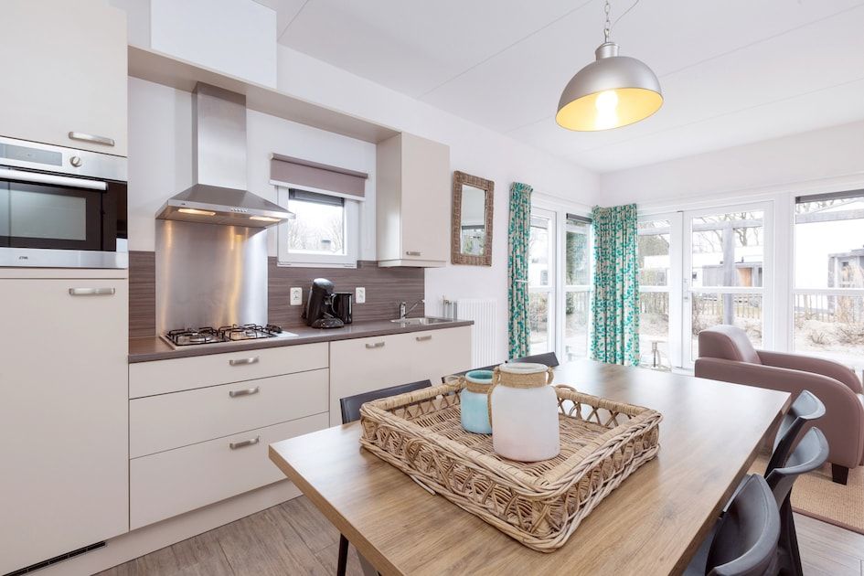 Moderne Kueche im Bungalow 6C, Ouddorp, Goeree-Overflakkee, Suedholland, mit heller Einrichtung und Blick auf die Terrasse.