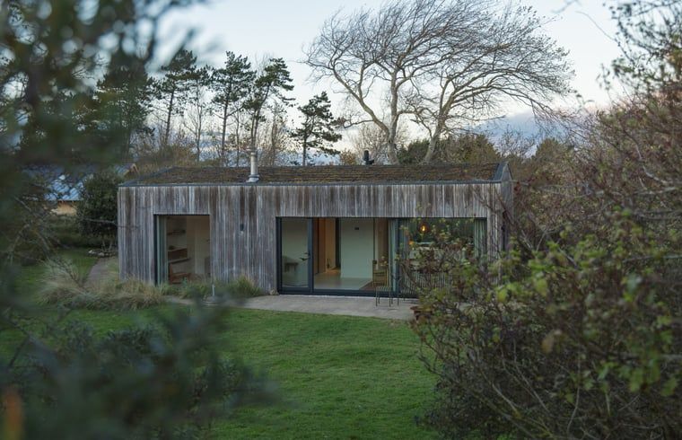Ferienhaus in Ouddorp, umgeben von Natur auf Goeree-Overflakkee, Suedholland, mit moderner Holzfassade und grossem Garten.