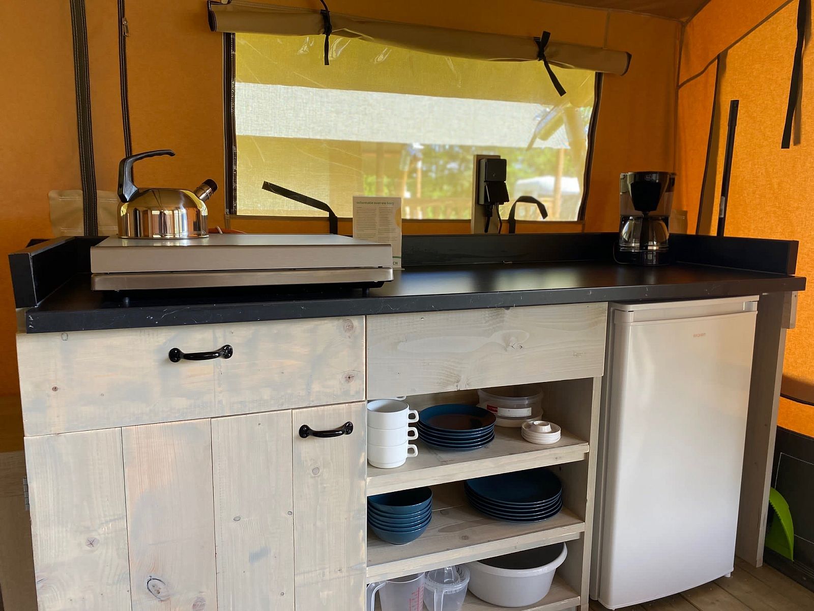 Moderne Kueche in Safaritent Zeeduin, einer Glamping Lodge in Ouddorp, Goeree-Overflakkee, Suedholland, mit Kuehlschrank und Kaffeemaschine.