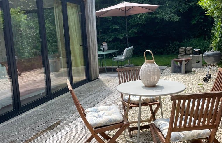 Veranda of House in Ouddorp, vacation accommodation in Ouddorp, South Holland with seating and green surroundings.