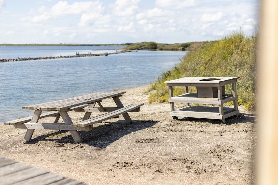 Rustieke picknickplek bij ECO Cottage in Ouddorp, Goeree-Overflakkee, met uitzicht op het water en omringd door natuurlijke schoonheid.