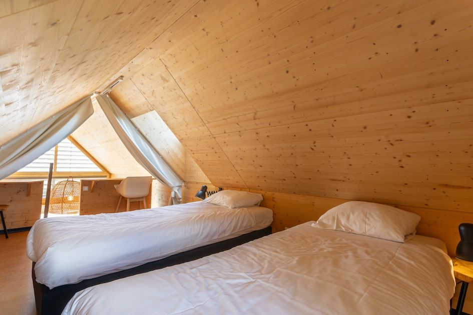 Gezellige slaapkamer in ECO Cottage, een vakantiehuis in Ouddorp, Goeree-Overflakkee, met houten interieur en comfortabele bedden.
