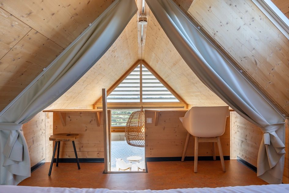 Gezellige zolderkamer in ECO Cottage, vakantiehuis in Ouddorp, Goeree-Overflakkee, met houten interieur en uitzicht op het terras.