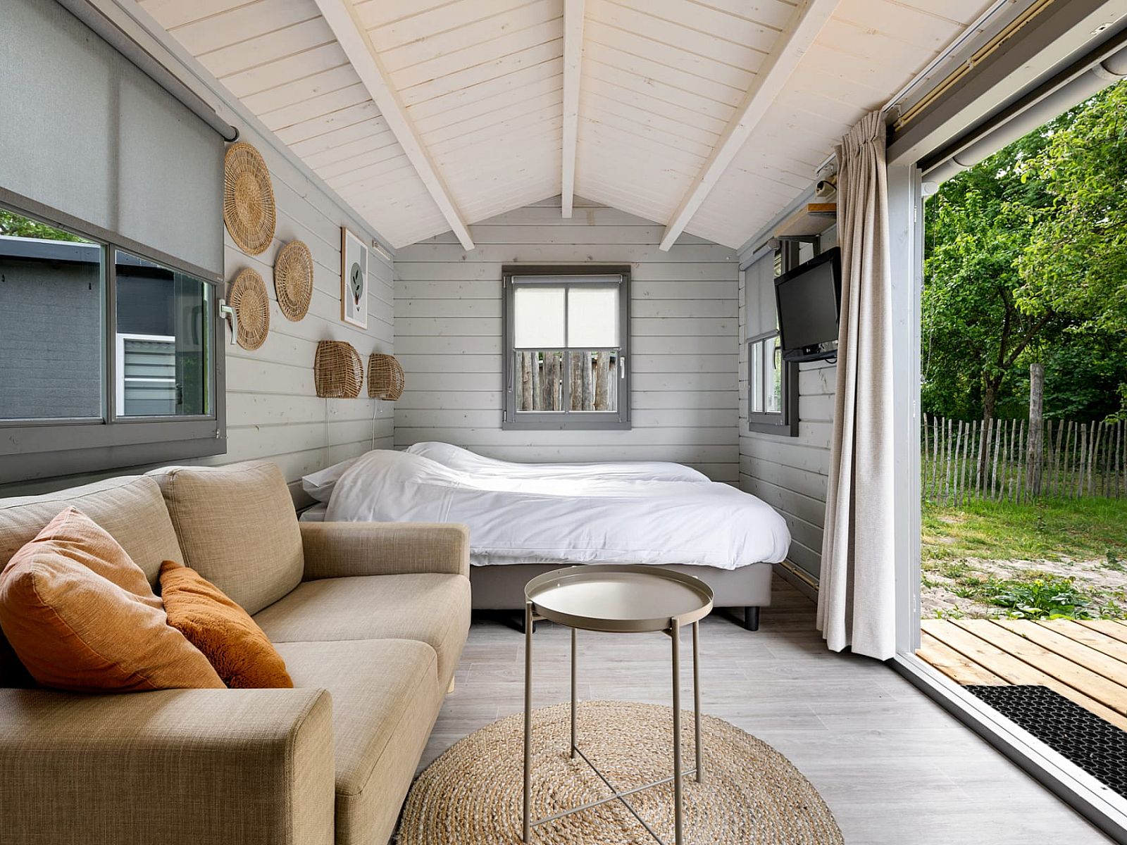 Innenbereich des Kampeerchalet de Zeekoet in Ouddorp mit gemuetlicher Sitzecke und Blick auf die Natur von Goeree-Overflakkee.