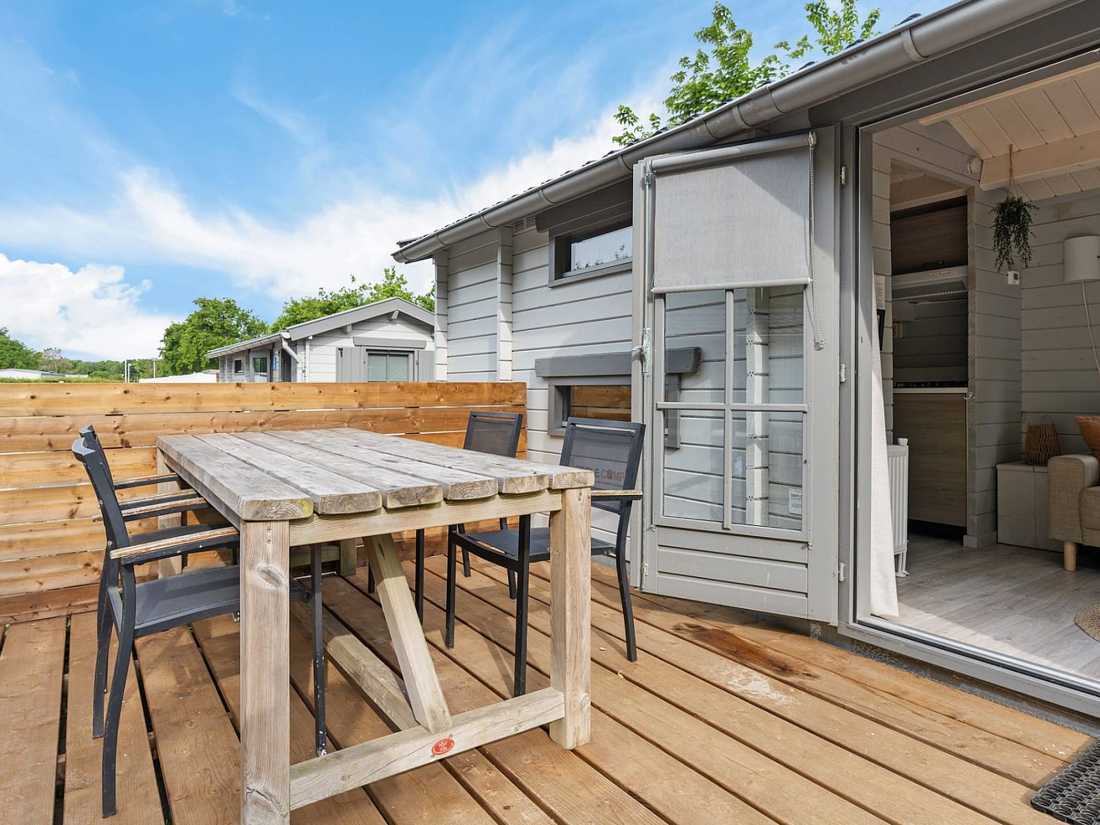 Terrasse des Kampeerchalet de Zeekoet in Ouddorp mit Esstisch und Stuehlen aus Holz, umgeben von der Natur von Goeree-Overflakkee.