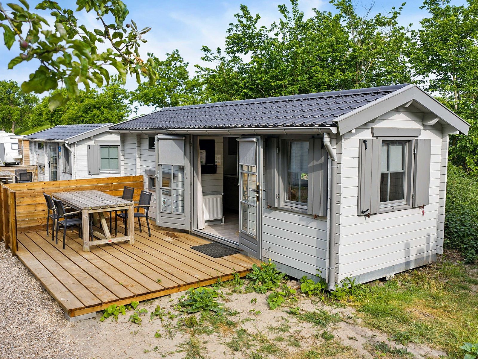 Aussenbereich des Campingplatzes Chalet de Zeekoet in Ouddorp mit einladender Terrasse und gruener Umgebung.