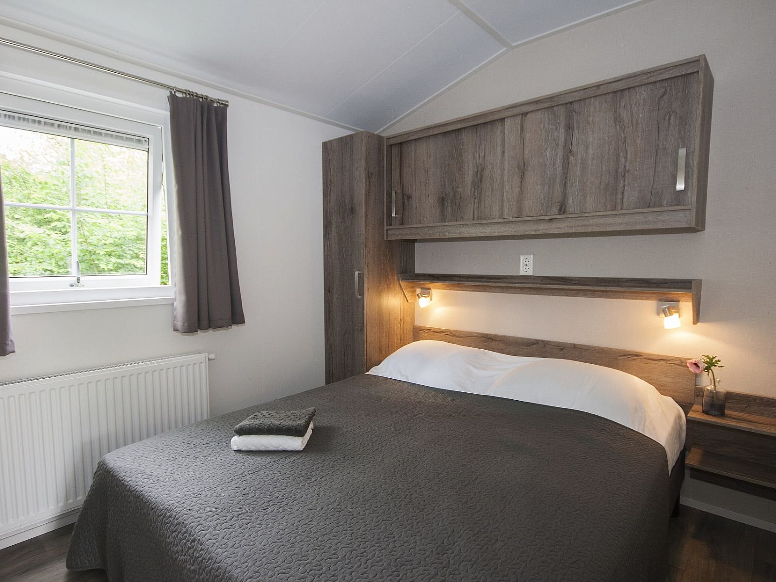 Gemuetliches Schlafzimmer im Chalet Ouddorp, einem Ferienhaus in Ouddorp, Goeree-Overflakkee, Suedholland, mit bequemem Bett und Holzinterieur.