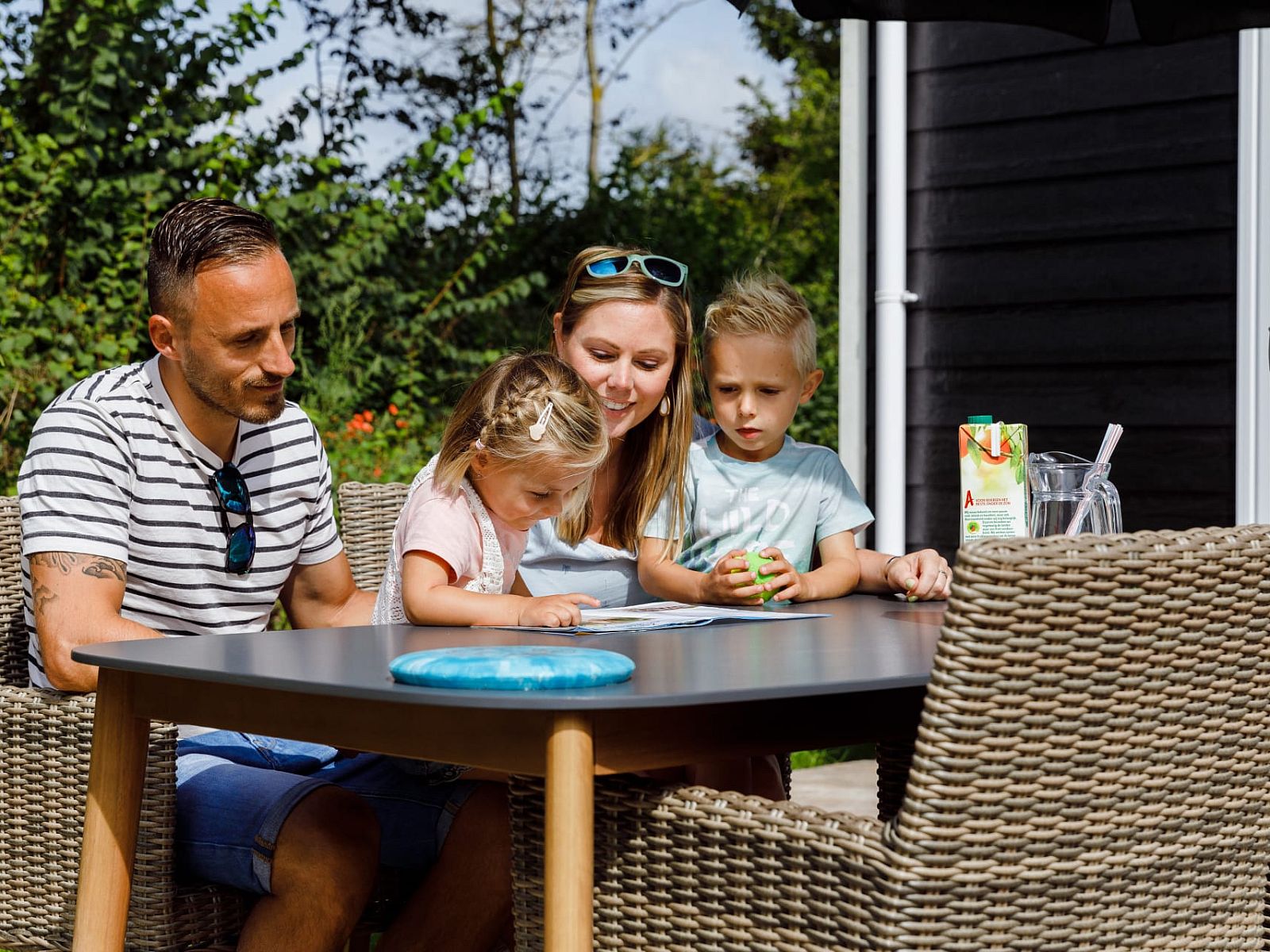Familie geniesst die Sonne auf der Terrasse von Chalet Ouddorp, einem Ferienhaus in Ouddorp, Goeree-Overflakkee, Suedholland.
