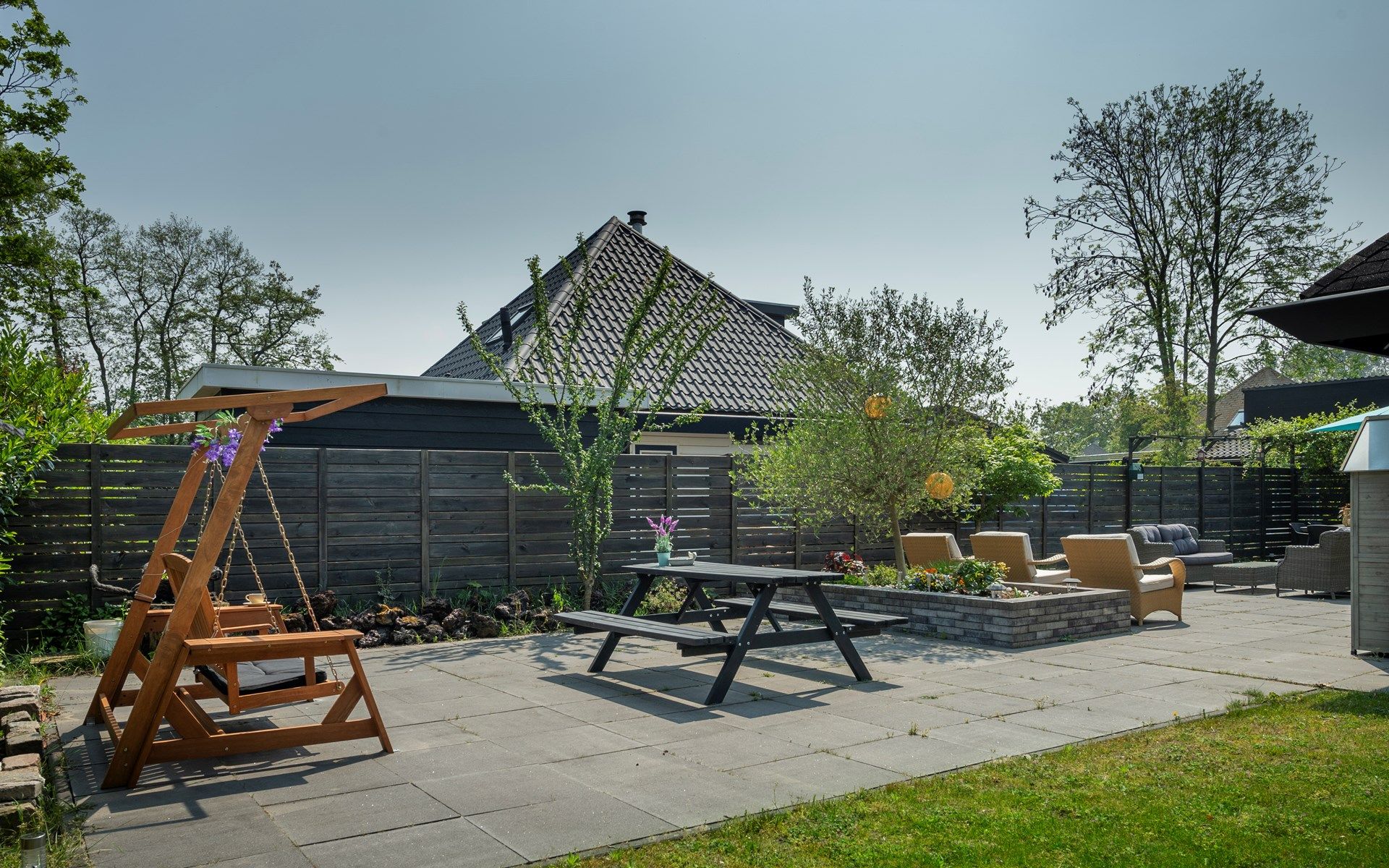 Gezellig terras met schommelstoel bij Vakantiewoning De Toekomst 107 'Siesta' in Ouddorp, perfect voor een ontspannen middag.