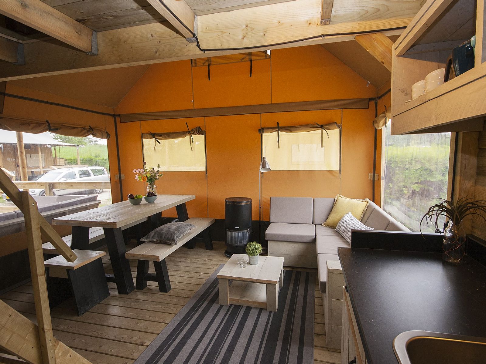 Gemuetlicher Innenbereich des Safarizeltes Duinroos in Ouddorp, Suedholland, mit bequemer Sitzecke und Holzinterieur.