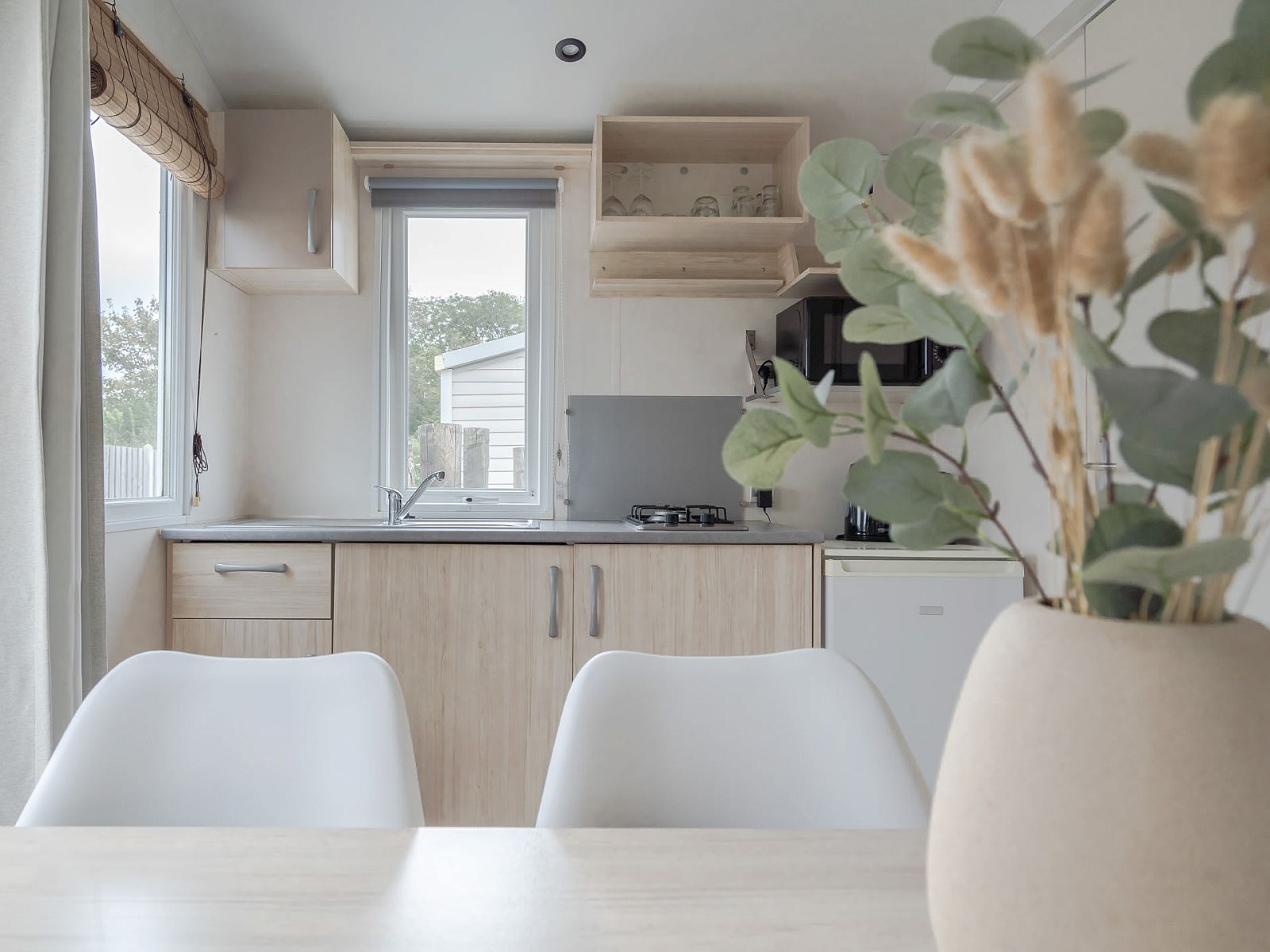 Innenbereich des Mobilheims der Kormoran in Ouddorp, Goeree-Overflakkee, mit moderner Kueche und Blick auf die Natur.