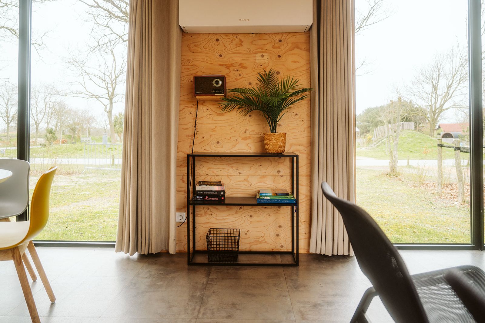 Interior of Duunroos vacation home in Ouddorp, with bookshelf and garden view.
