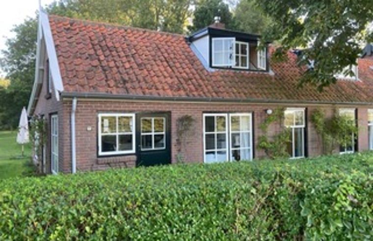 Gemuetliches Ferienhaus in Goedereede mit roten Dachziegeln und gruener Hecke in Suedholland.