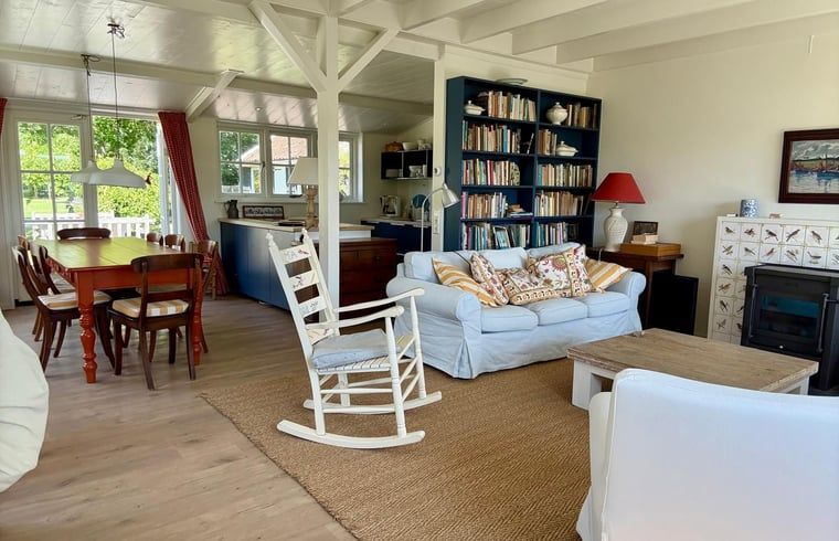 Gemuetliches Wohnzimmer im Ferienhaus in Goedereede mit Kamin und Buecherregal.