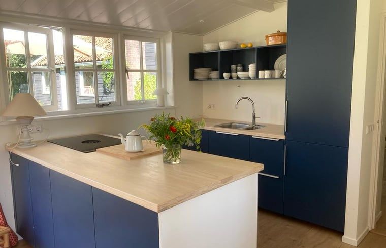 Moderne Kueche im Ferienhaus in Goedereede mit blauen Schraenken und hellen Arbeitsplatten.