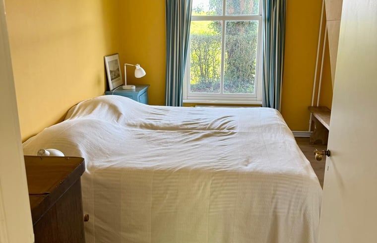 Gemuetliches Zimmer im Dachgeschoss eines Ferienhauses in Goedereede mit Holzboden und Dachfenster.