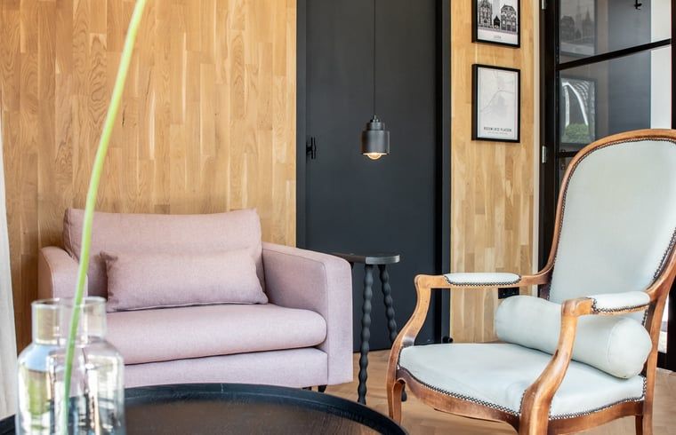 Gezellige zitruimte in Vakantiehuisje in Reeuwijk, Groene hart, Zuid-Holland, met stijlvolle houten muren en comfortabele fauteuils.