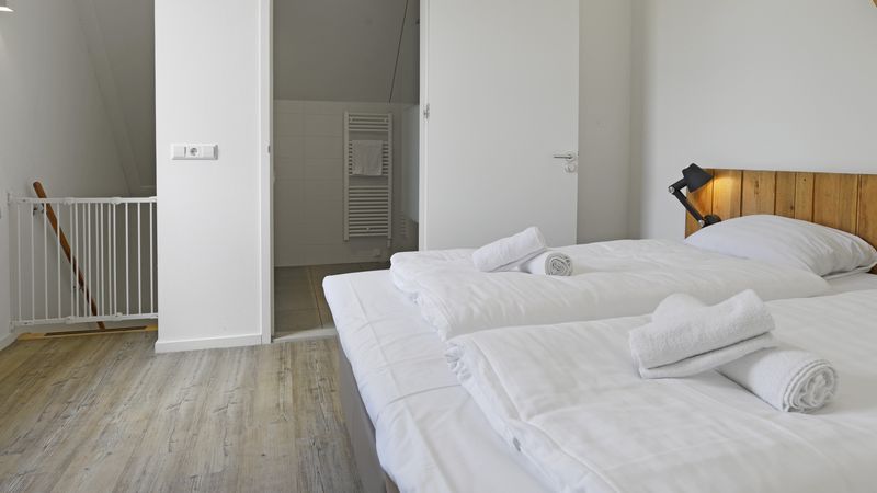 Slaapkamer met toegang tot badkamer in De Reeuwijkse Plassen 2-persoons waterwoning 2C, Reeuwijk, Zuid-Holland.