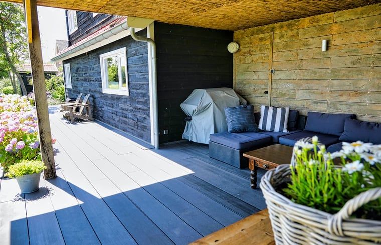Geniet van de overdekte veranda bij Vakantiehuis in Gouderak, gelegen in het Groene Hart van Zuid-Holland, met comfortabele zithoek.