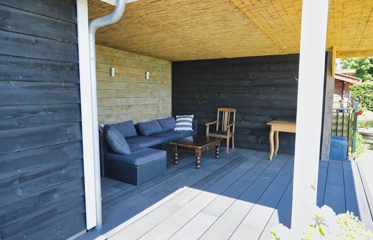 Ontspan op de knusse veranda van Vakantiehuis in Gouderak, gelegen in het Groene Hart van Zuid-Holland, met comfortabele zitplekken.