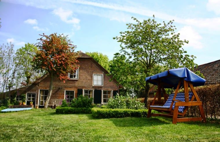 Vakantiehuisje in Vlist, gelegen in het Groene Hart van Zuid-Holland, met een prachtige tuin en schommelbank omringd door natuur.