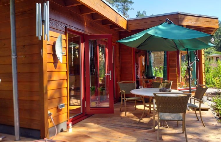 Terras van Vakantiehuisje in Groesbeek met parasol en zitplaatsen, ideaal voor ontspanning in Gelderland.