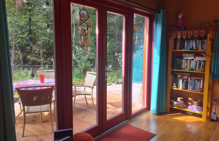 Uitzicht vanuit de woonkamer van Vakantiehuisje in Groesbeek met toegang tot het terras in Gelderland.