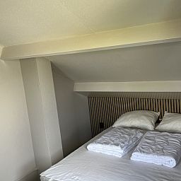 Sfeervolle slaapkamer in TXL Huisje 299, een vakantiehuis in De Cocksdorp, Texel, met een comfortabel bed en rustieke houten accenten.