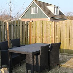 Gezellig terras bij Onder de vuurtoren 115, vakantiehuis in De Cocksdorp, Texel met houten schutting en tuinmeubilair.